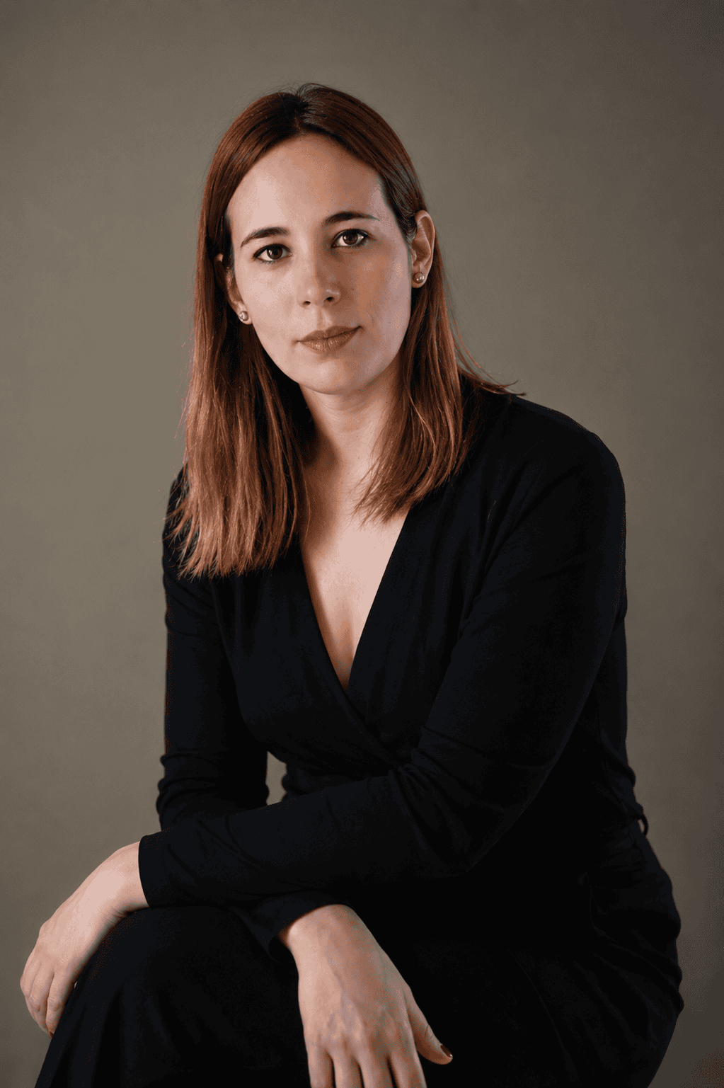 Lise Duarte Nuñez, orchestral percussionist and educator, seated editorial portrait in black on a neutral background